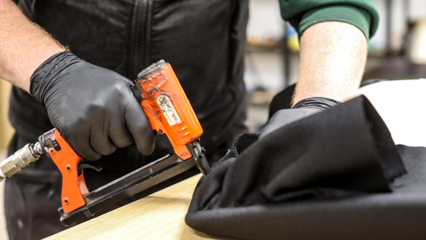 Image of seat of and office chair being reupholstered using a staple gun